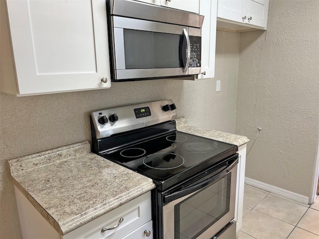 kitchen featuring white cabinets, light tile patterned floors, and stainless steel appliances