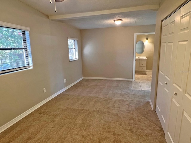 unfurnished room with light colored carpet, a textured ceiling, and a wealth of natural light