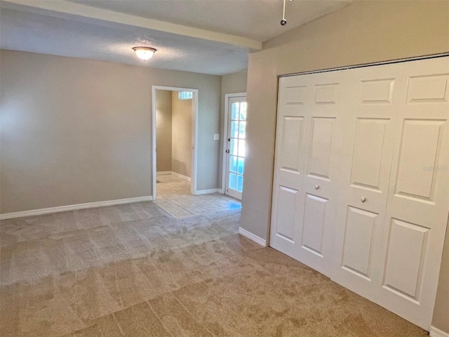 unfurnished bedroom with a textured ceiling, light colored carpet, and a closet