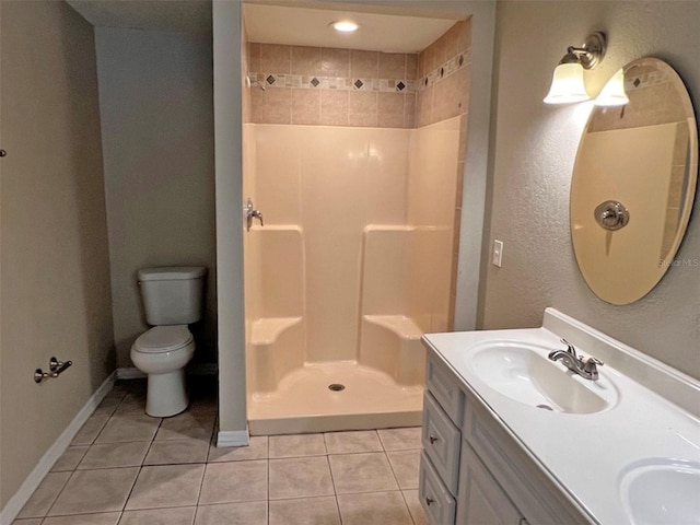 bathroom with toilet, vanity, tiled shower, and tile patterned floors