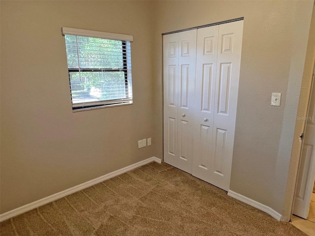 unfurnished bedroom featuring a closet and light colored carpet