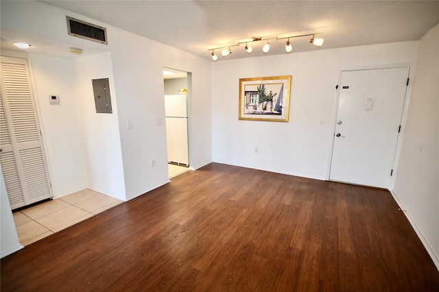 interior space with a textured ceiling, electric panel, and light hardwood / wood-style flooring