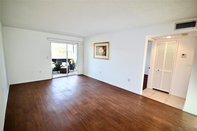 empty room with a textured ceiling and light wood-type flooring