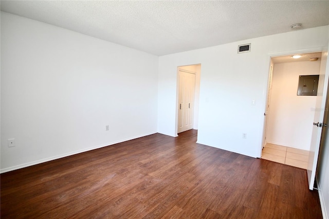 unfurnished room with electric panel, dark wood-type flooring, and a textured ceiling