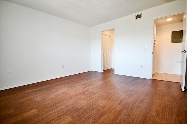 unfurnished room with a textured ceiling, dark hardwood / wood-style flooring, and electric panel