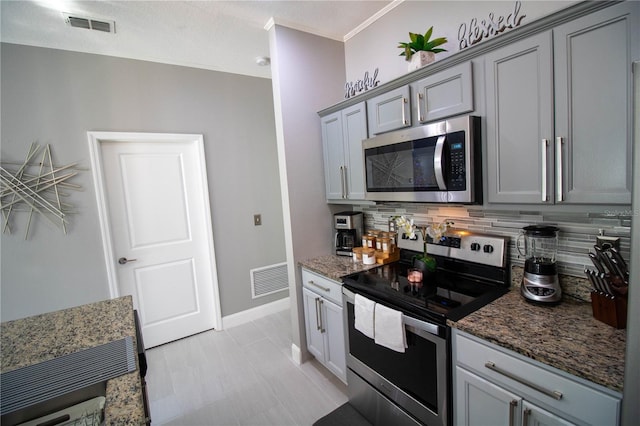 881 Orchid Grove Blvd, Davenport, FL 33837 - kitchen with stainless steel appliances, gray cabinets, tasteful backsplash, and dark stone countertops