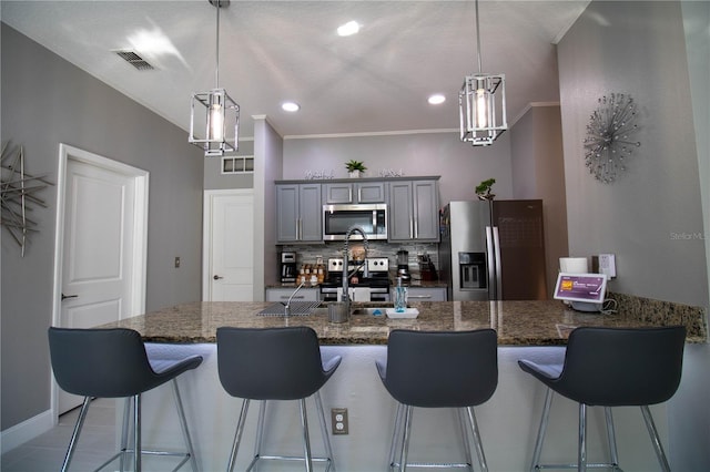881 Orchid Grove Blvd, Davenport, FL 33837 - kitchen with stainless steel appliances, gray cabinets, a kitchen breakfast bar, dark stone countertops, and backsplash