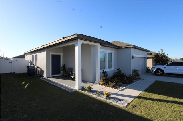 view of side of property featuring a yard, stucco siding, concrete driveway, an attached garage, and fence