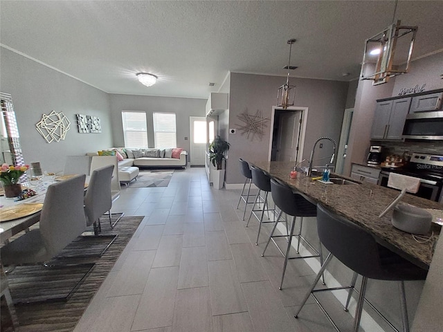 881 Orchid Grove Blvd, Davenport, FL 33837 - kitchen featuring appliances with stainless steel finishes, a breakfast bar, dark stone countertops, open floor plan, and a textured ceiling