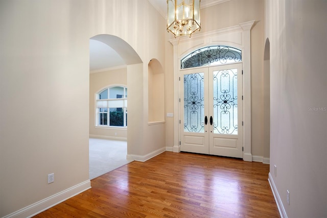 entryway with hardwood / wood-style floors, ornamental molding, and french doors