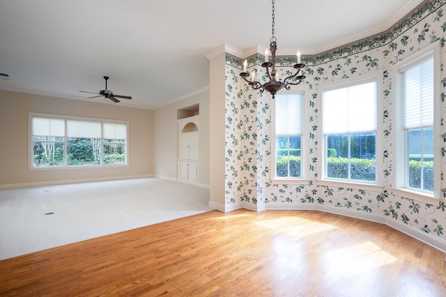 empty room with ceiling fan with notable chandelier, hardwood / wood-style flooring, a wealth of natural light, and ornamental molding