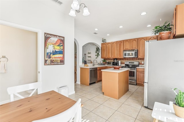 kitchen with light tile patterned floors, stainless steel appliances, a kitchen island, and tasteful backsplash