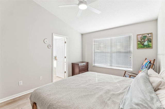 bedroom featuring connected bathroom, ceiling fan, light hardwood / wood-style floors, and vaulted ceiling