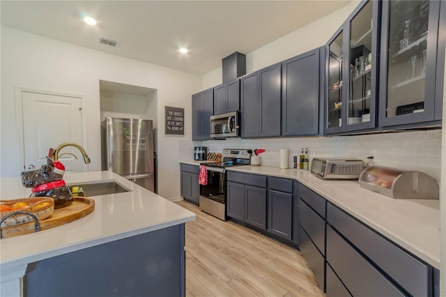 kitchen with decorative backsplash, stainless steel appliances, light hardwood / wood-style flooring, and sink