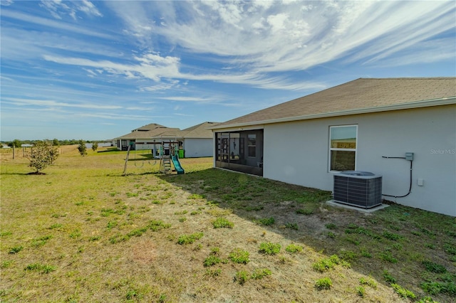 view of yard featuring a playground, central air condition unit, and a sunroom