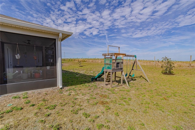 view of yard featuring a rural view, a playground, and a sunroom