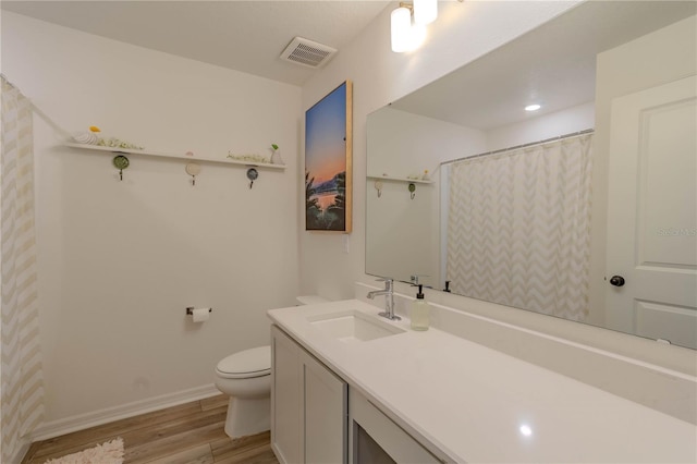 bathroom with hardwood / wood-style floors, vanity, and toilet