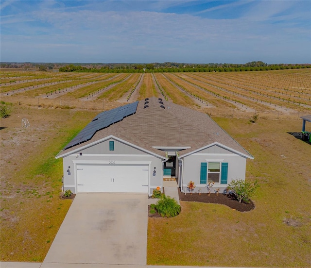 single story home featuring solar panels, a rural view, and a garage