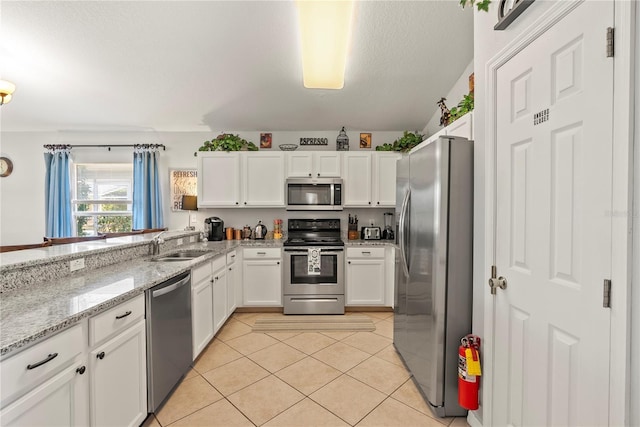 kitchen featuring white cabinets, sink, light tile patterned floors, light stone countertops, and appliances with stainless steel finishes