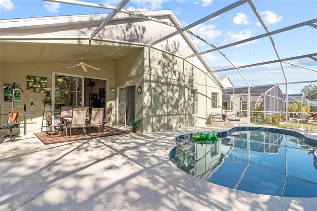 view of swimming pool with ceiling fan, a patio, and glass enclosure