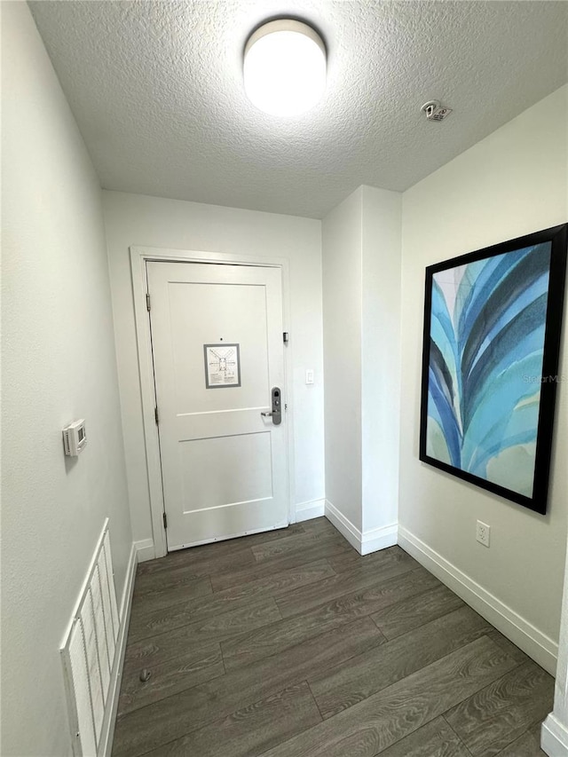 doorway to outside featuring a textured ceiling and dark wood-type flooring