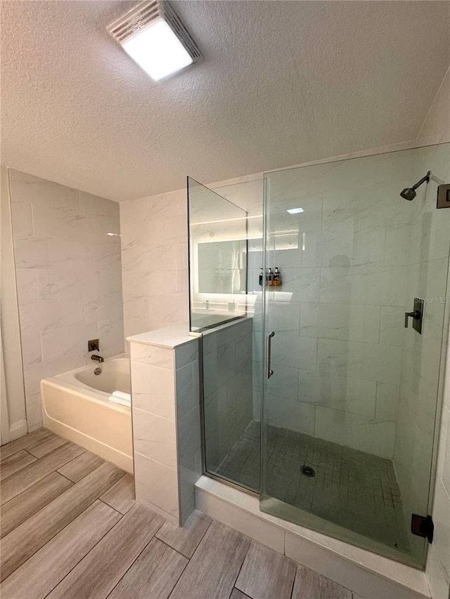 bathroom with plus walk in shower and a textured ceiling