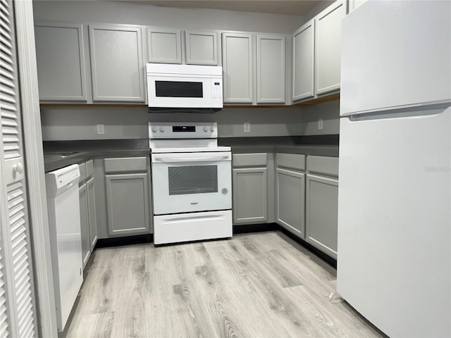 kitchen featuring gray cabinetry, light wood-type flooring, and white appliances