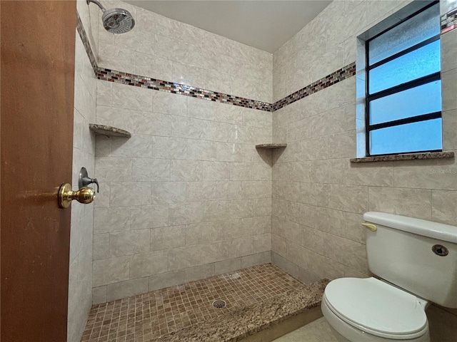 bathroom featuring a tile shower and toilet