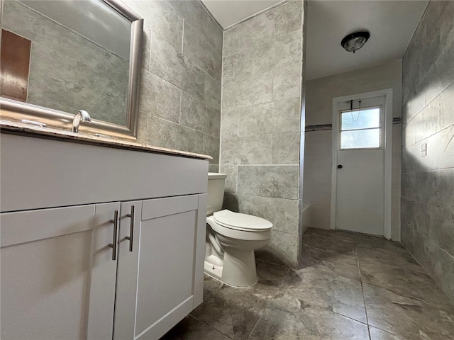 bathroom featuring vanity, toilet, and tile walls