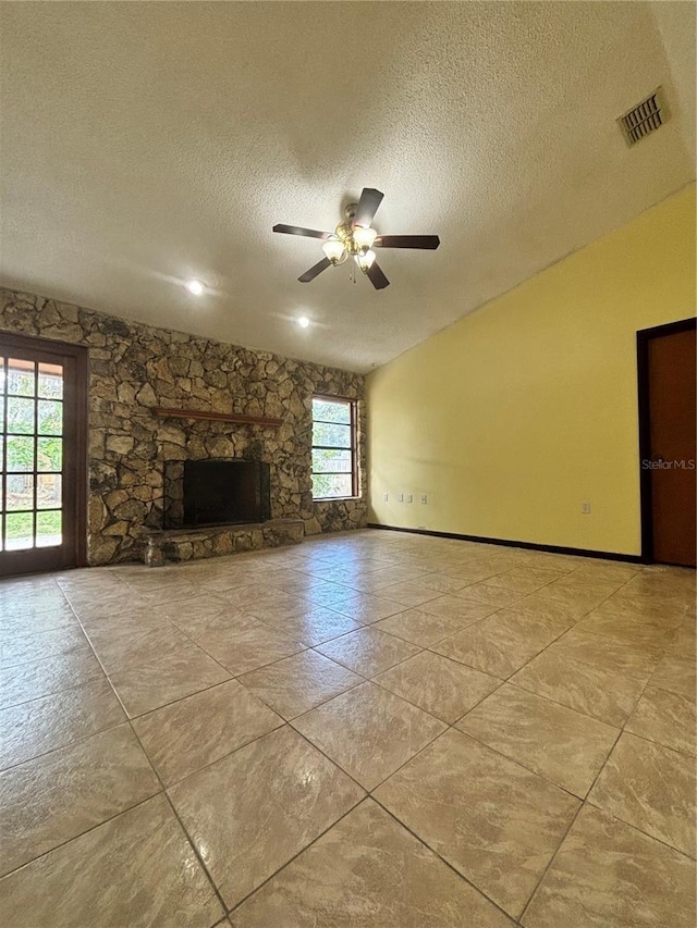 unfurnished living room with plenty of natural light, a stone fireplace, and a textured ceiling