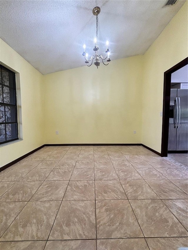 tiled empty room with vaulted ceiling, a textured ceiling, and a notable chandelier