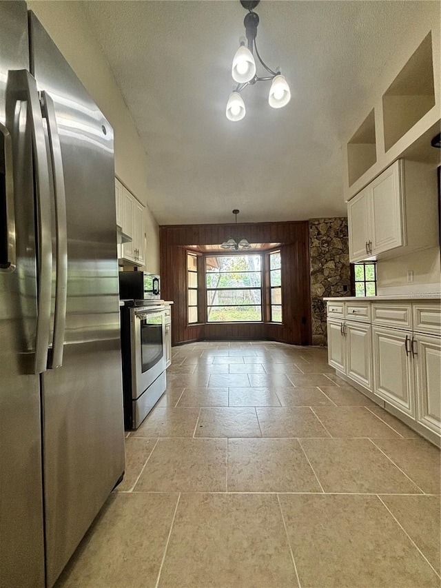 kitchen with appliances with stainless steel finishes, decorative light fixtures, white cabinetry, and a notable chandelier