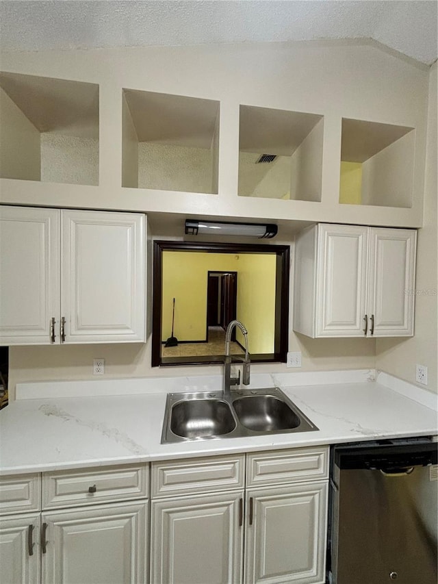 kitchen with dishwasher, sink, vaulted ceiling, light stone counters, and white cabinetry