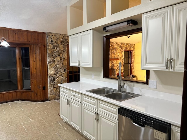 kitchen featuring a textured ceiling, white cabinetry, stainless steel dishwasher, and sink