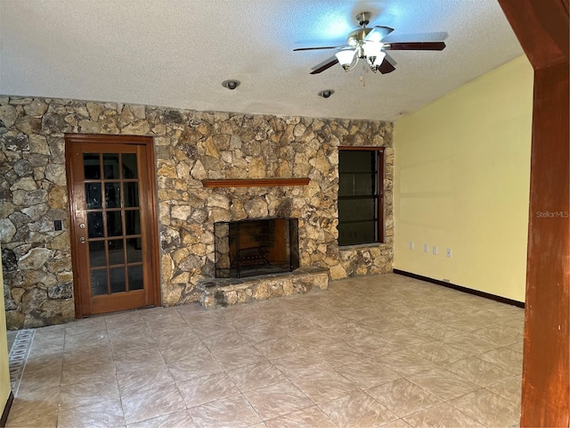 unfurnished living room featuring a textured ceiling, a stone fireplace, and ceiling fan