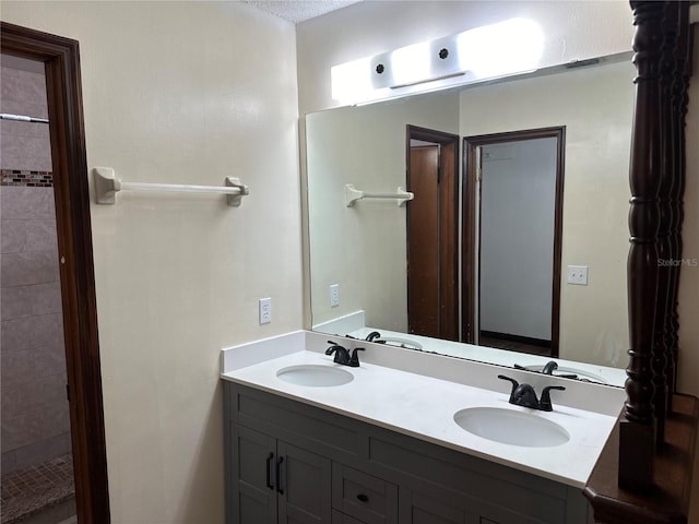 bathroom with vanity, tiled shower, and a textured ceiling