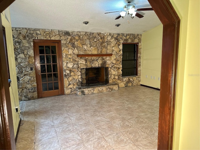 unfurnished living room with a stone fireplace, ceiling fan, and a textured ceiling