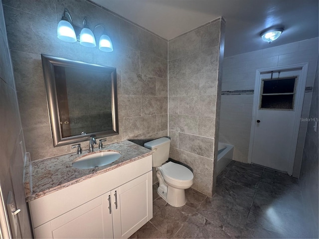 bathroom with vanity, toilet, and tile walls