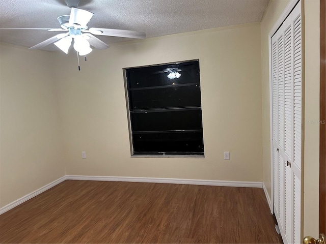 unfurnished bedroom featuring ceiling fan, a closet, dark wood-type flooring, and a textured ceiling