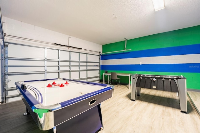 rec room with a textured ceiling and light wood-type flooring