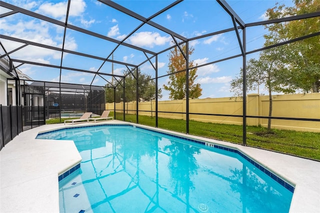 view of swimming pool with glass enclosure, a patio area, and a lawn