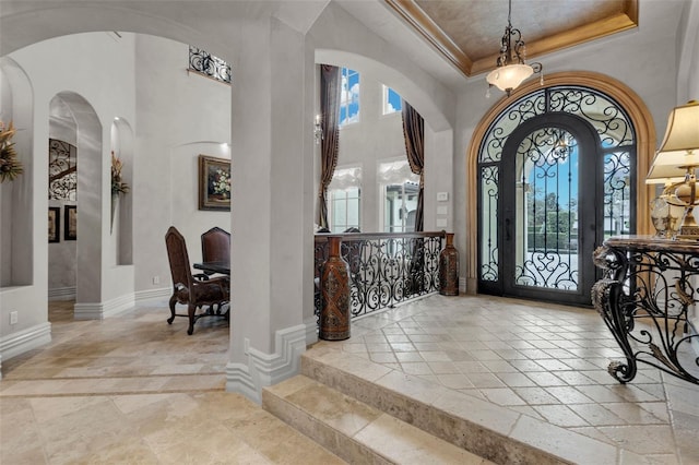 foyer with a towering ceiling, crown molding, and french doors