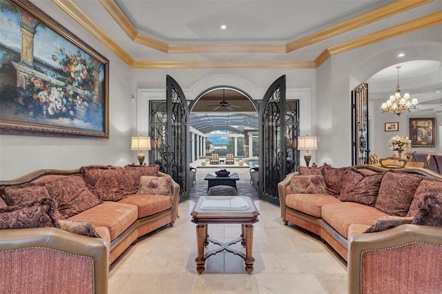 living room with a tray ceiling, crown molding, and ceiling fan with notable chandelier