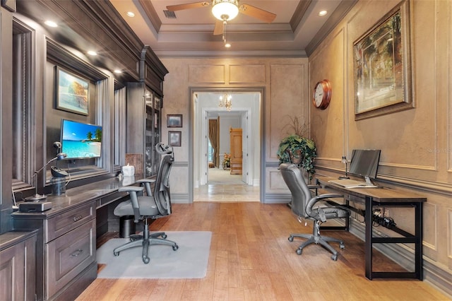 office with light hardwood / wood-style floors, a raised ceiling, and crown molding