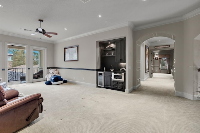 living room featuring light carpet, crown molding, ceiling fan, bar, and beverage cooler