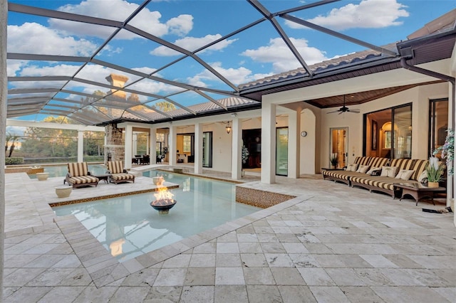 view of swimming pool with a patio, glass enclosure, ceiling fan, and an outdoor living space with a fire pit