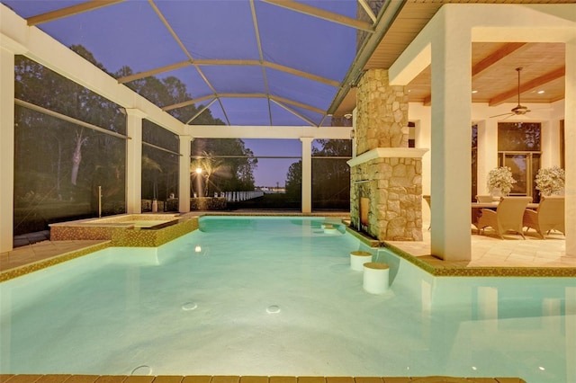 pool at dusk with an in ground hot tub, a patio, ceiling fan, and a lanai