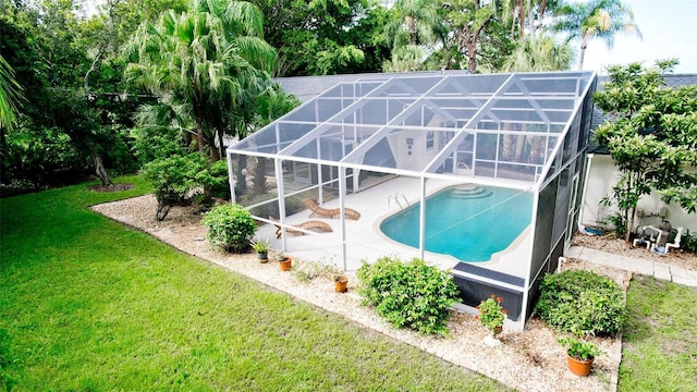 view of pool with glass enclosure, a yard, and a patio