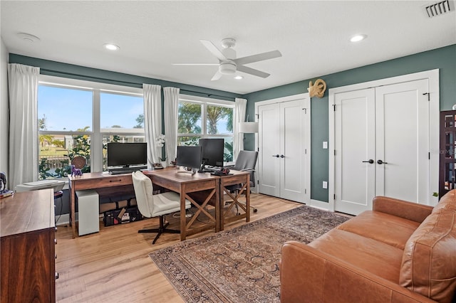 home office with ceiling fan, light wood-type flooring, and a textured ceiling