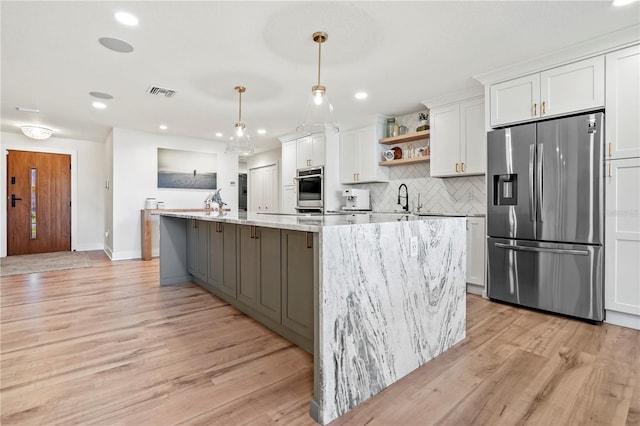 kitchen with stainless steel appliances, white cabinets, a spacious island, and decorative light fixtures